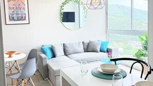 A modern kitchen with a dining area, a sofa, and a large window with a view. - Cozy Apartment One Block from the Ocean in Salguero Beach, Santa Marta (Gaira)