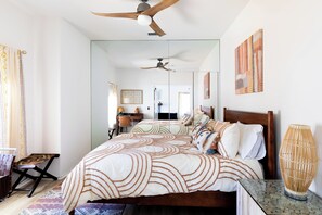 A bedroom with a large bed, a ceiling fan, a bedside table, a mirror, and a wall-mounted artwork. - 4-bedroom house in tranquil Palm Springs with Mountain View's and a pool (Palm Springs)