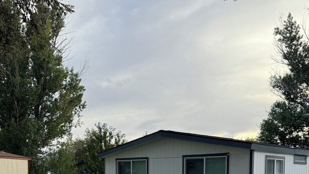 A single-story mobile home with a fenced yard, a gravel driveway, and a wooden deck. - Short term rentals and corporate housing.  Up to 25% discounts for longer stays (Winnemucca)