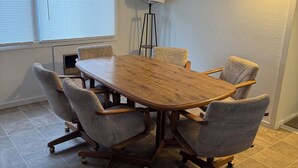A conference room with a wooden table, four upholstered chairs, a standing lamp, and a window with blinds. - Short term rentals and corporate housing.  Up to 25% discounts for longer stays (Winnemucca)