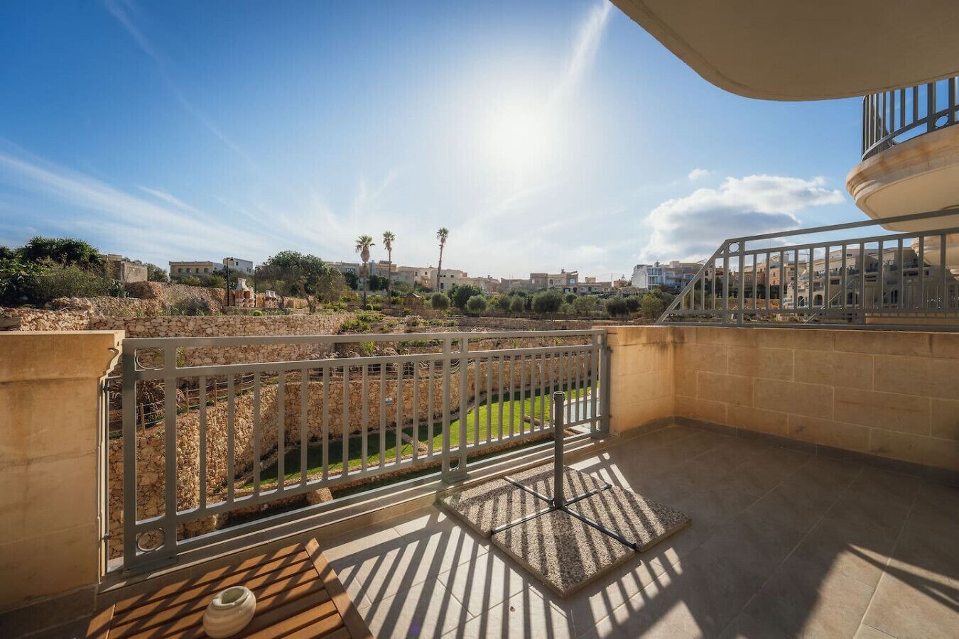 Un balcon donnant sur un paysage urbain, un mur en pierre et une rambarde en métal.