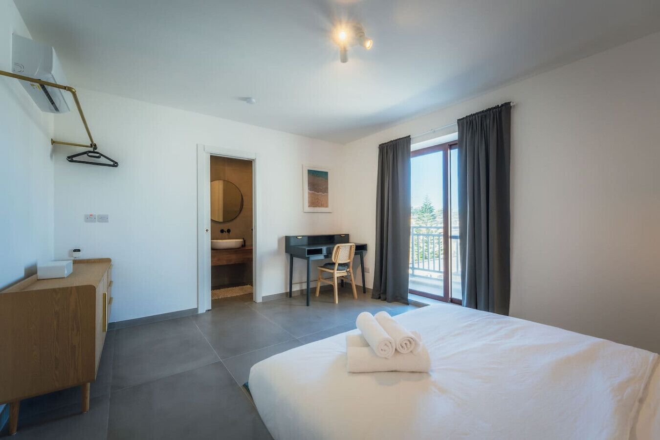 A hotel room with a bed, a desk, a chair, a wardrobe, and a bathroom.