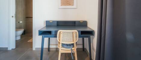 A modern room with a desk, chair, and a framed picture of a beach.
