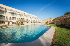 A hotel with a swimming pool, multiple balconies, and a stone retaining wall. - Qala Skyview Penthouse Pool Sunsets BBQ Area (Qala)