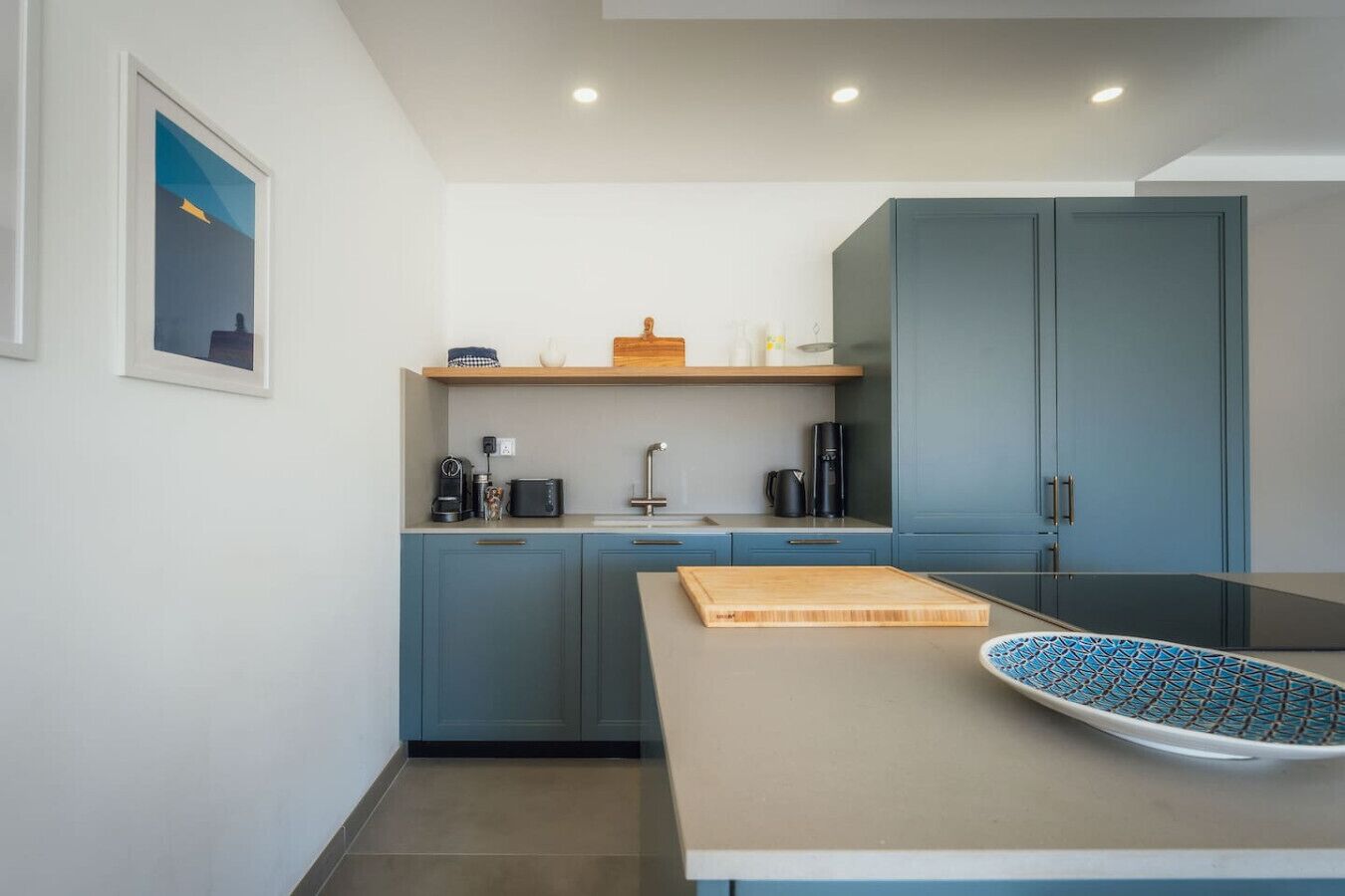 Een moderne keuken met blauwe kastjes, een houten aanrecht en een koffieapparaat.