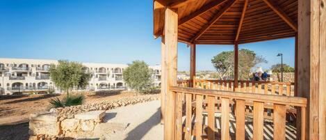 A wooden gazebo with a view of a building complex and a clear sky.