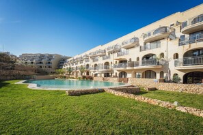 A hotel with a swimming pool surrounded by a stone wall and green grass. - Qala Skyview Penthouse Pool Sunsets BBQ Area (Qala)
