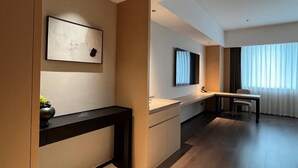 A modern hotel room with a minimalist design, featuring a desk, a chair, a flat-screen TV mounted on the wall, and a large window with sheer curtains. - SHILIA STAY YANCHENG (Yancheng)