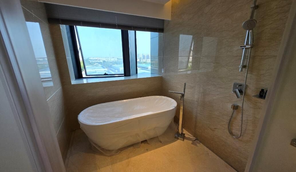 Un baño moderno con una bañera independiente, ducha y un amplio ventanal con vistas a la ciudad.