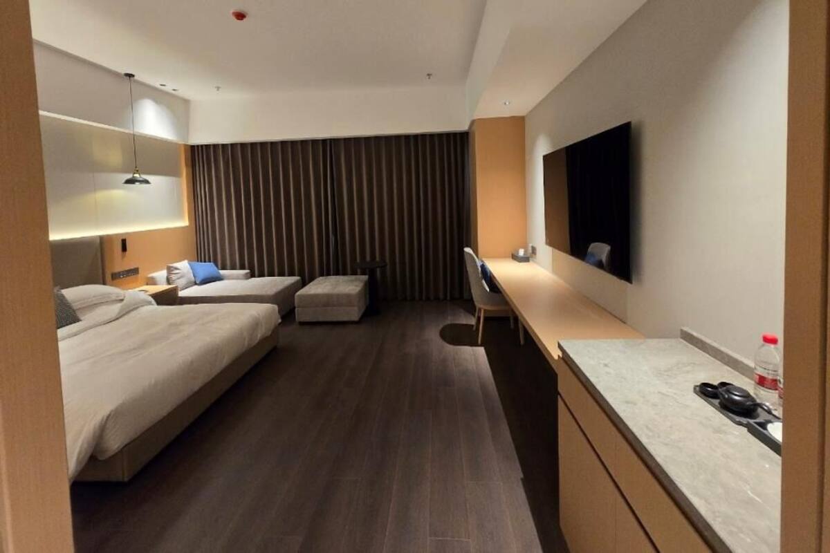 A hotel room with two beds, a desk, a chair, a TV, and a curtain.