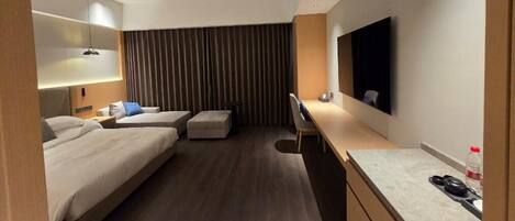 A hotel room with two beds, a desk, a chair, a TV, and a curtain.