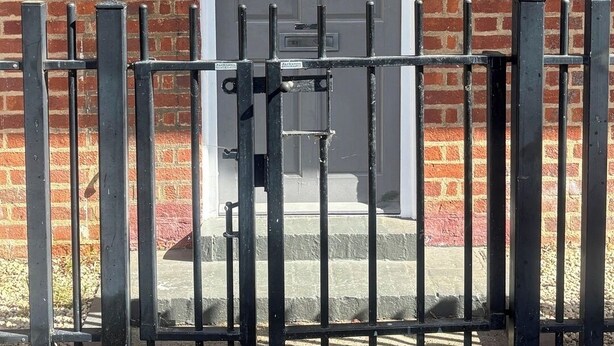 A brick building with a grey door, a metal gate, and a small window to the left. - Spacious 5-Bed Home near Stockwell Tube Station (Greater London)