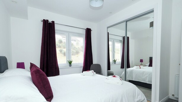 Une chambre d’hôtel moderne avec un grand lit, une chaise, un bureau et un grand miroir.