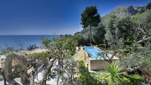 Una piscina rodeada de vegetación mediterránea, con vistas a un paisaje costero.