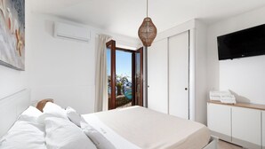 Un dormitorio con cama, televisor, armario y vista al exterior.
