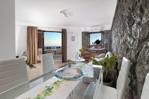 Ein modernes Wohnzimmer mit Esstisch, einer Couch und Blick auf das Meer.