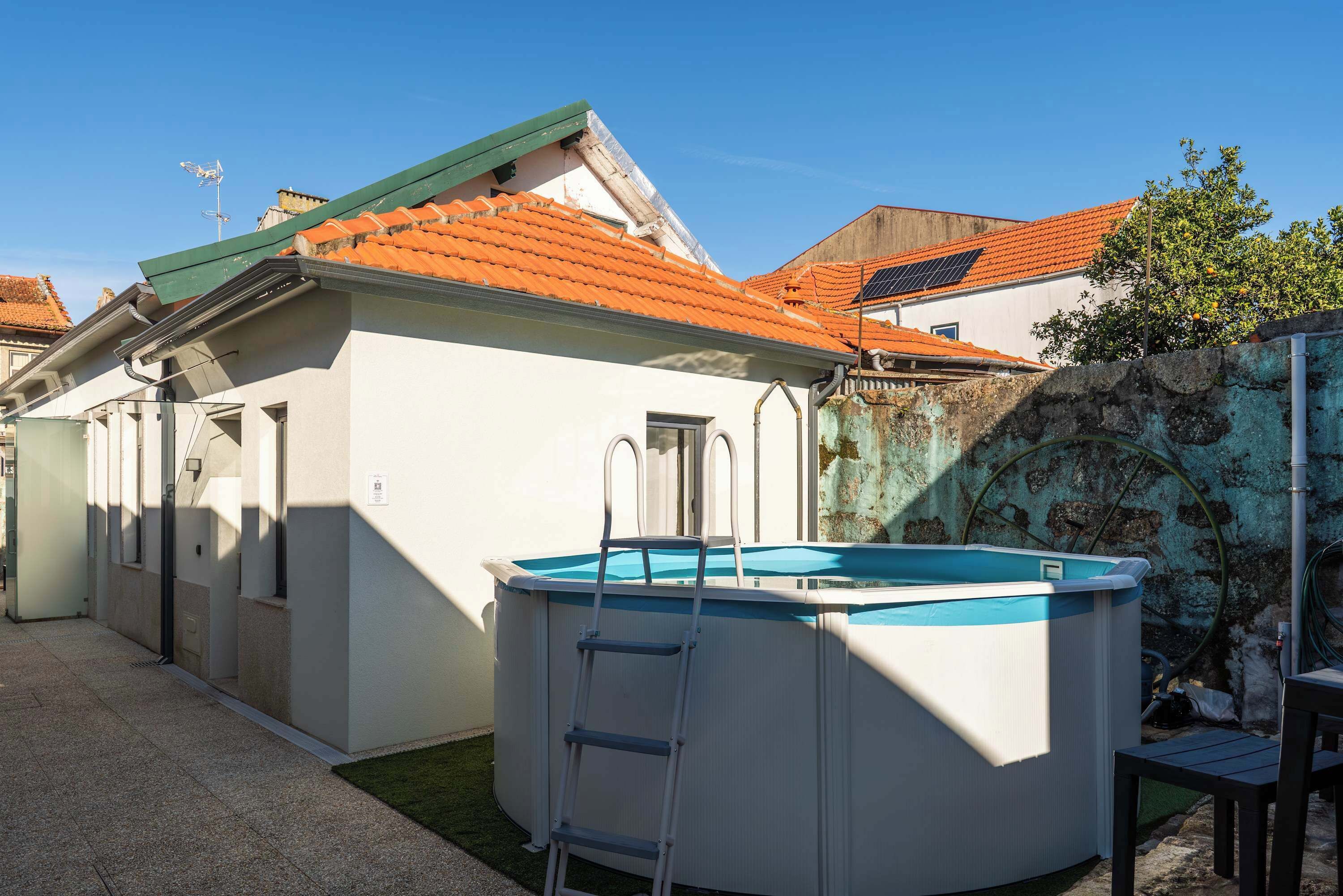 A residential property with a swimming pool, a ladder, and a stone wall.