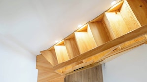 A ceiling with wooden beams and recessed lighting.