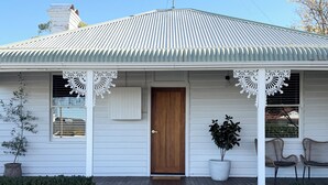Ein eingeschossiges Haus mit einer Veranda, einer Holztür und einem kleinen Garten.