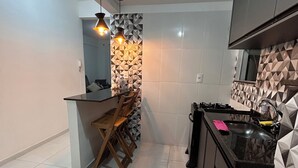 A modern kitchen with a dining area, featuring a black countertop, white tiled walls, and geometric patterned backsplash. - Cozy apartment in Muriaé (Muriaé)
