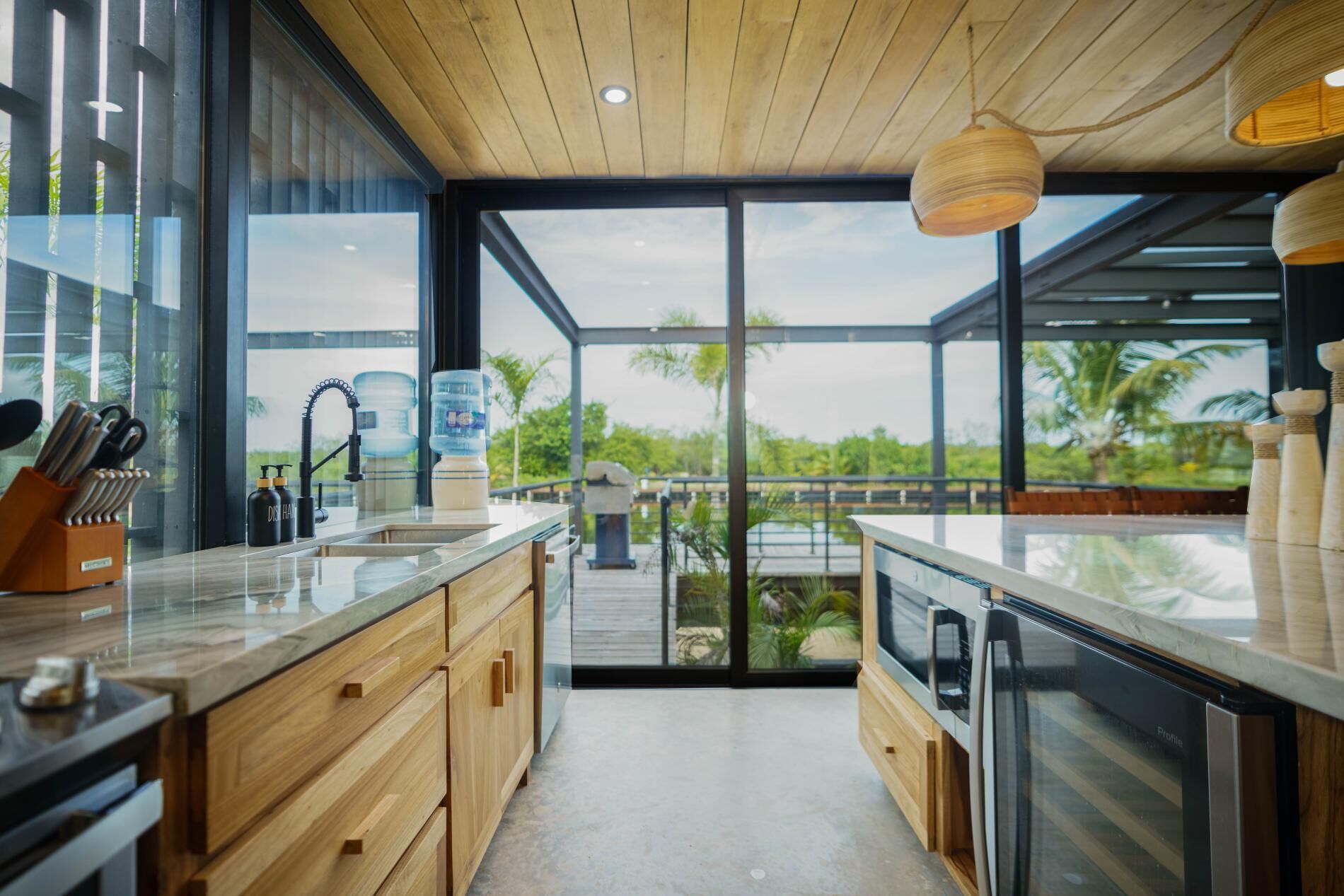 A modern kitchen with wooden cabinets, a stainless steel oven, and a large window overlooking a lush landscape.