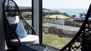 A balcony with wicker chairs and a view of the ocean. - Ocean View Retreat at Greens Beach (Greens Beach)