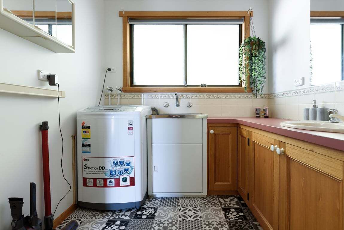 Cocina compacta con lavadora, un refrigerador pequeño y una ventana con una planta.