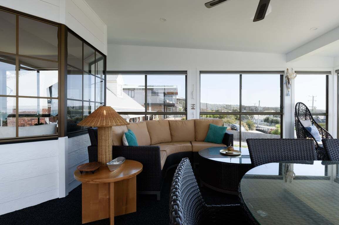 A modern living room with a large window, a sofa, a round table, and a chair.