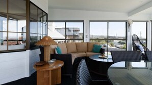 A modern living room with a large window, a sofa, a round table, and a chair. - Ocean View Retreat at Greens Beach (Greens Beach)