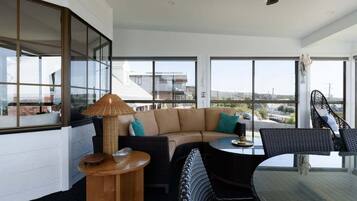 A modern living room with a large window, a sofa, a round table, and a chair.