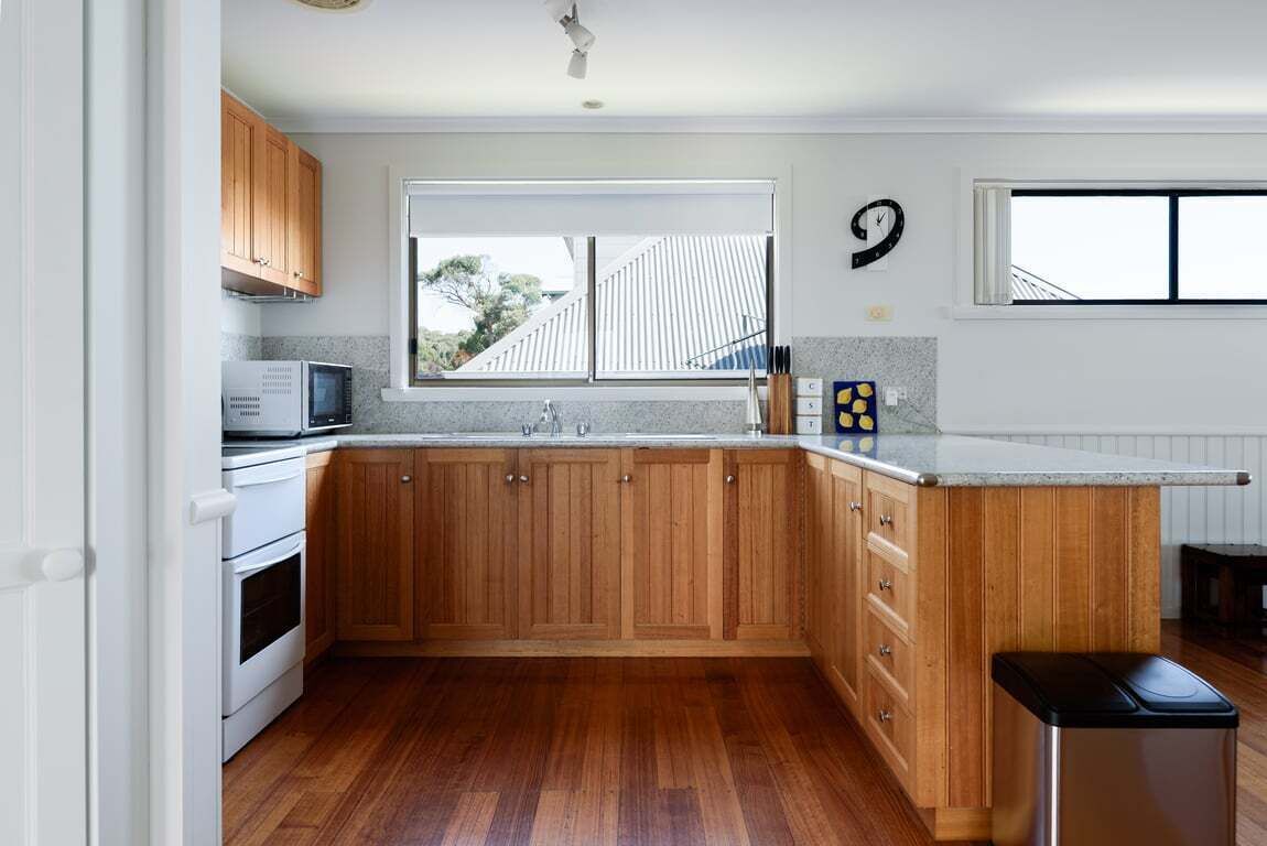 A kitchen with wooden cabinets, a microwave, a sink, and a window.