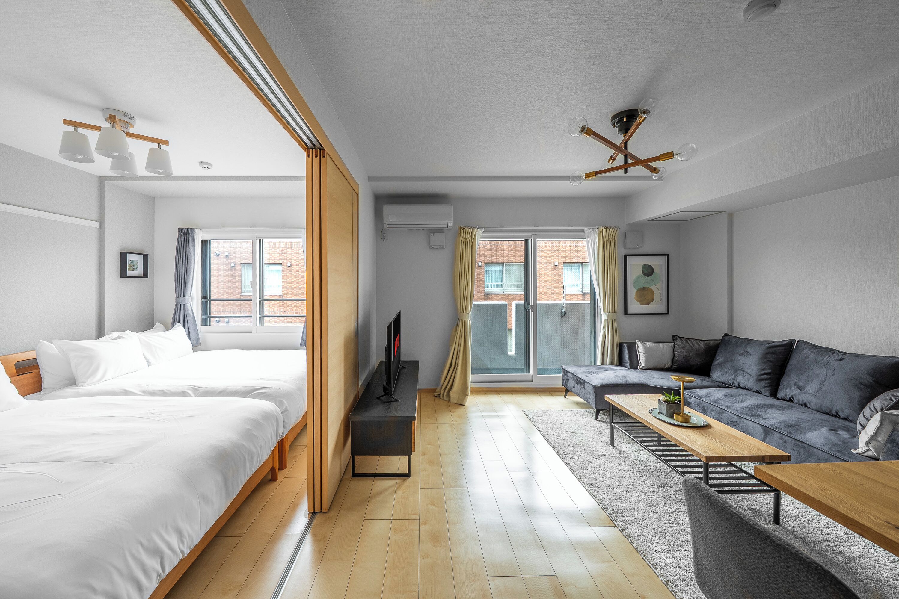 A modern hotel room with a bed, a sofa, a TV, and a dining table.
