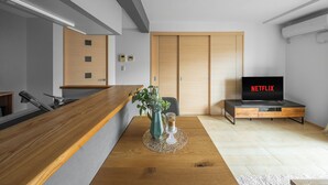 Un soggiorno moderno con un tavolino in legno, un vaso con fiori, una TV che mostra 'NETFLIX' e un armadio con ante scorrevoli.