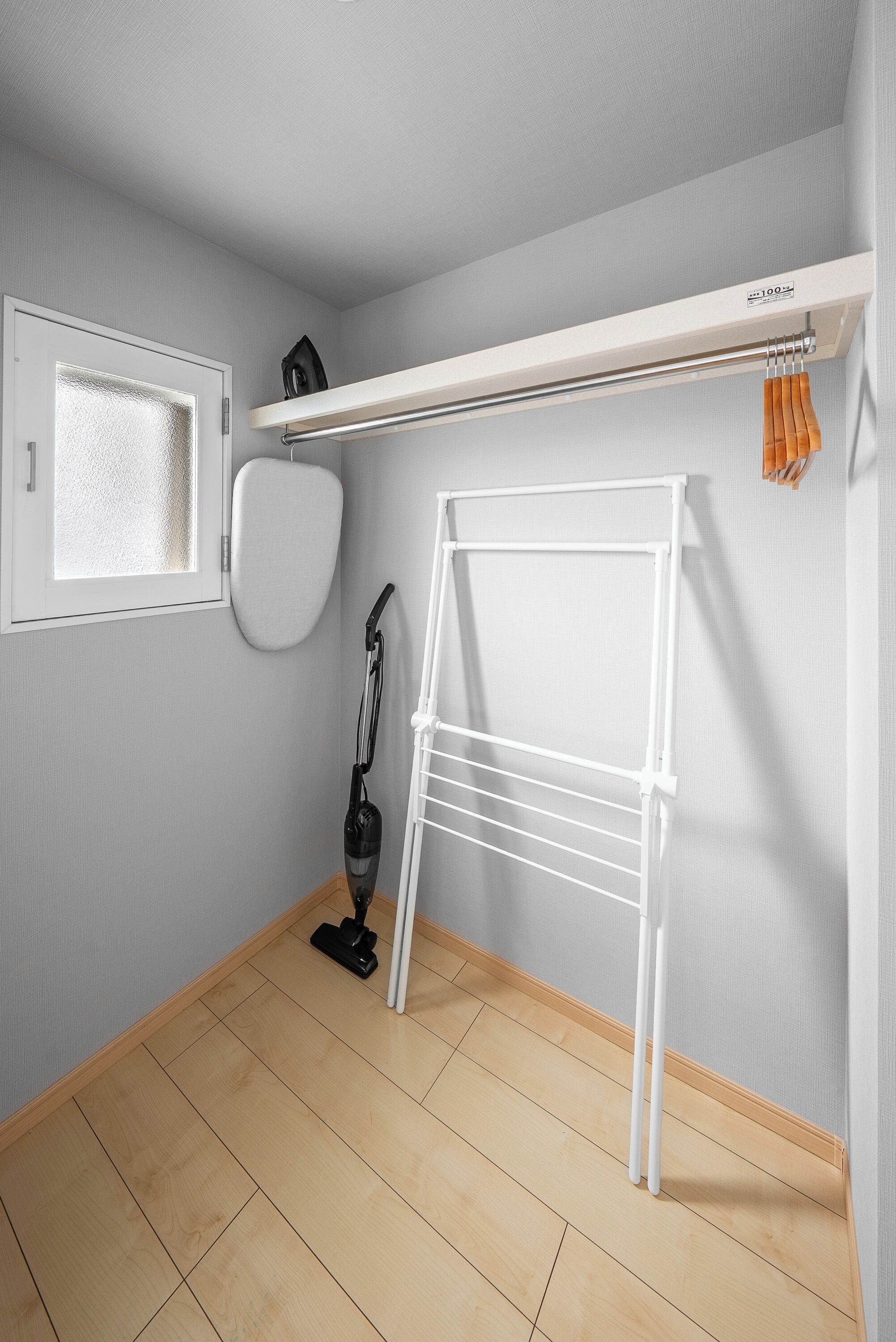 Ein Zimmer mit einer weißen Heizung, einem Staubsauger und einem Wäscheständer an der Wand.