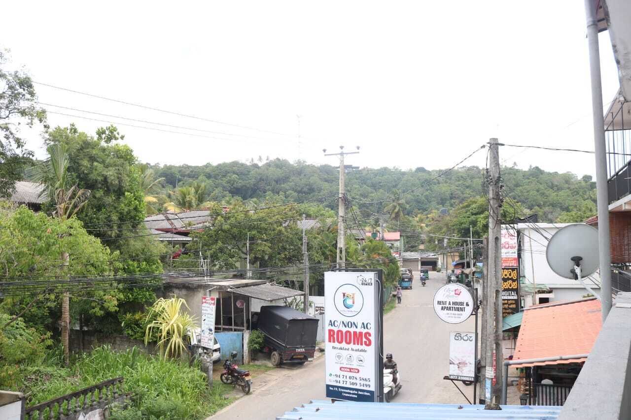 Vista de la calle con un cartel que indica habitaciones con y sin aire acondicionado, un hospital y una casa y apartamentos de alquiler.