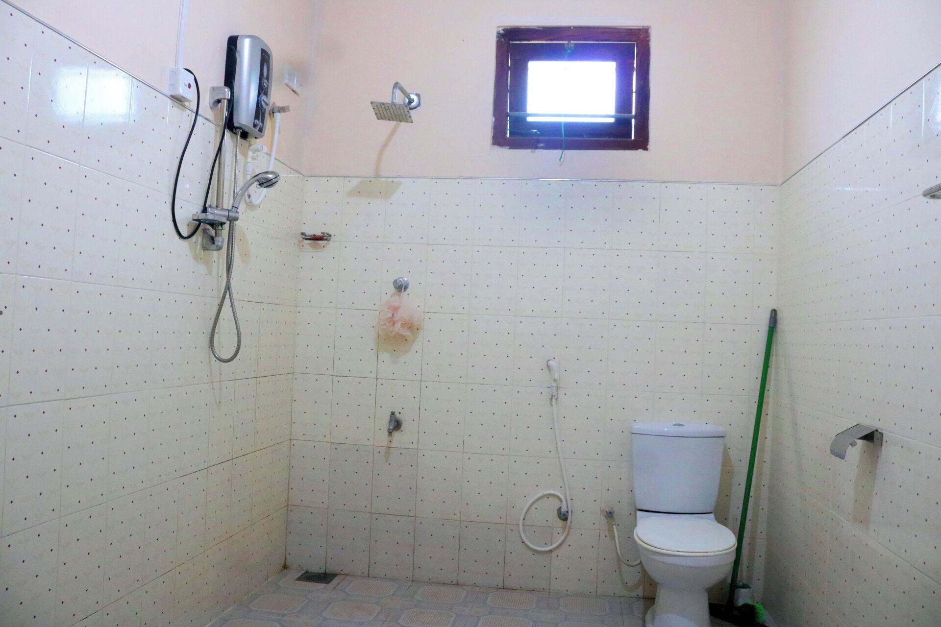 A small bathroom with a toilet, a shower, and a window.