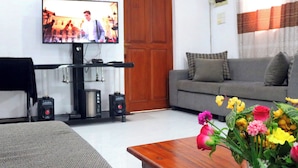 A living room with a television, a sofa, a coffee table, and a floral arrangement. - Unaway Holiday Home (Unawatuna)