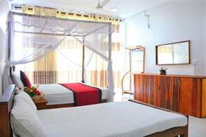 A hotel room with a bed, a wooden dresser, and a window with curtains. - Unaway Holiday Home (Unawatuna)