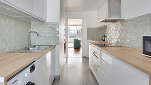 Une cuisine moderne avec des meubles blancs, un évier en acier inoxydable et un lave-vaisselle encastré.