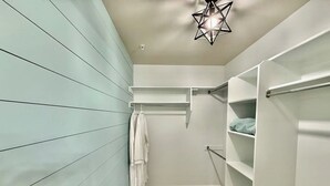 A walk-in closet with light blue paneling, wooden flooring, and white shelving units. - The Grove Getaway-Centrally Located (Pleasant Grove)