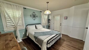 A bedroom with a bed, a wooden table, and a hanging light fixture. - The Grove Getaway-Centrally Located (Pleasant Grove)