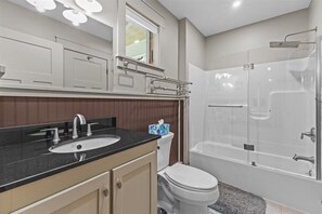 A modern bathroom with a sink, toilet, and glass-enclosed shower. - Peaceful Forest Escape by Lake Elmore (Elmore)
