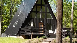 Une cabane dotée d’un toit à forte pente, de grandes fenêtres et d’une terrasse en bois.
