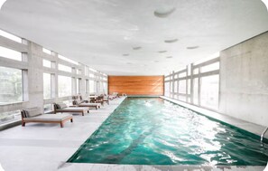 A swimming pool with lounge chairs and a wooden wall in a modern indoor setting. - La Condesa: beautiful loft, GYM & Pool, wifi 800 Mb. Symmetrical. (Ciudad de México)