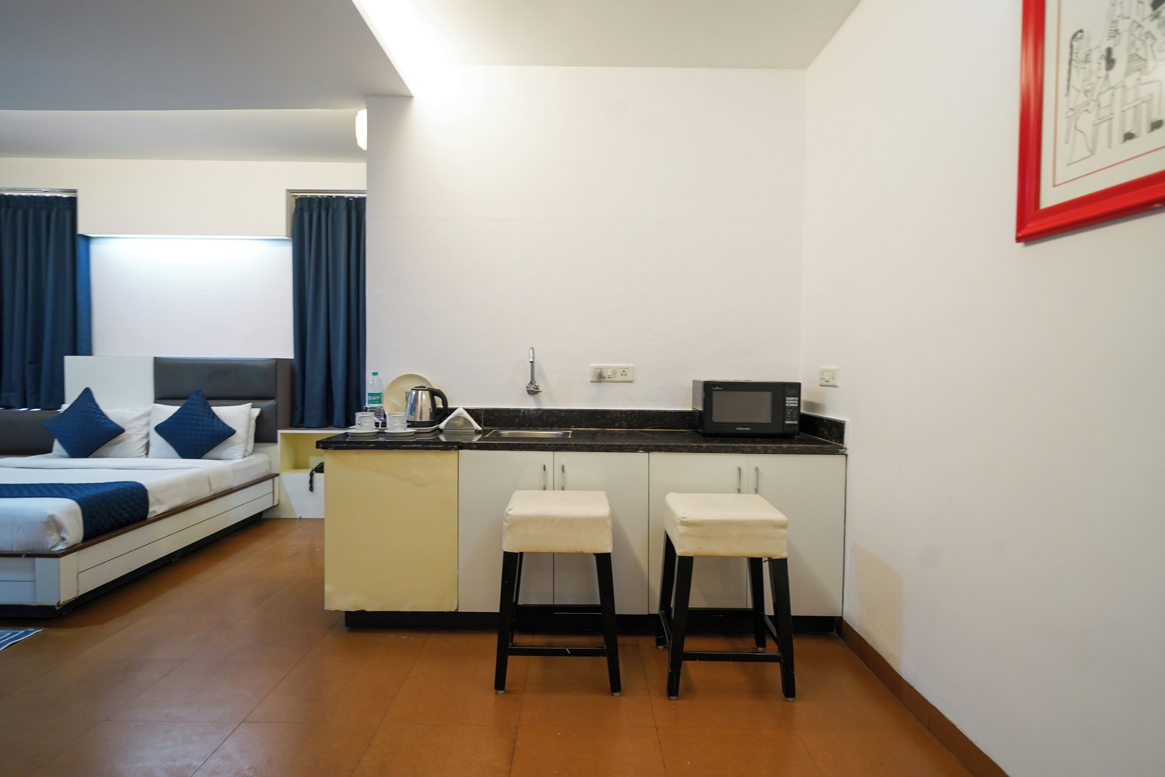 A compact hotel room with a bed, a kitchenette, and a small bar area.