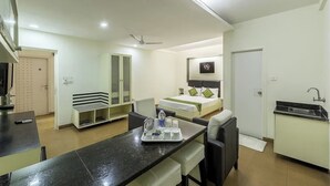 A hotel room with a bed, a desk with a tray of toiletries, a kitchenette, and a bathroom. - VH Hotels Domlur (Bengaluru)