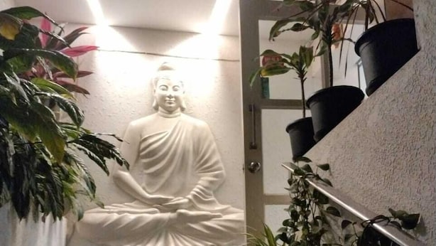 A Buddha statue on a staircase with potted plants around. - VH Hotels Domlur (Bengaluru)