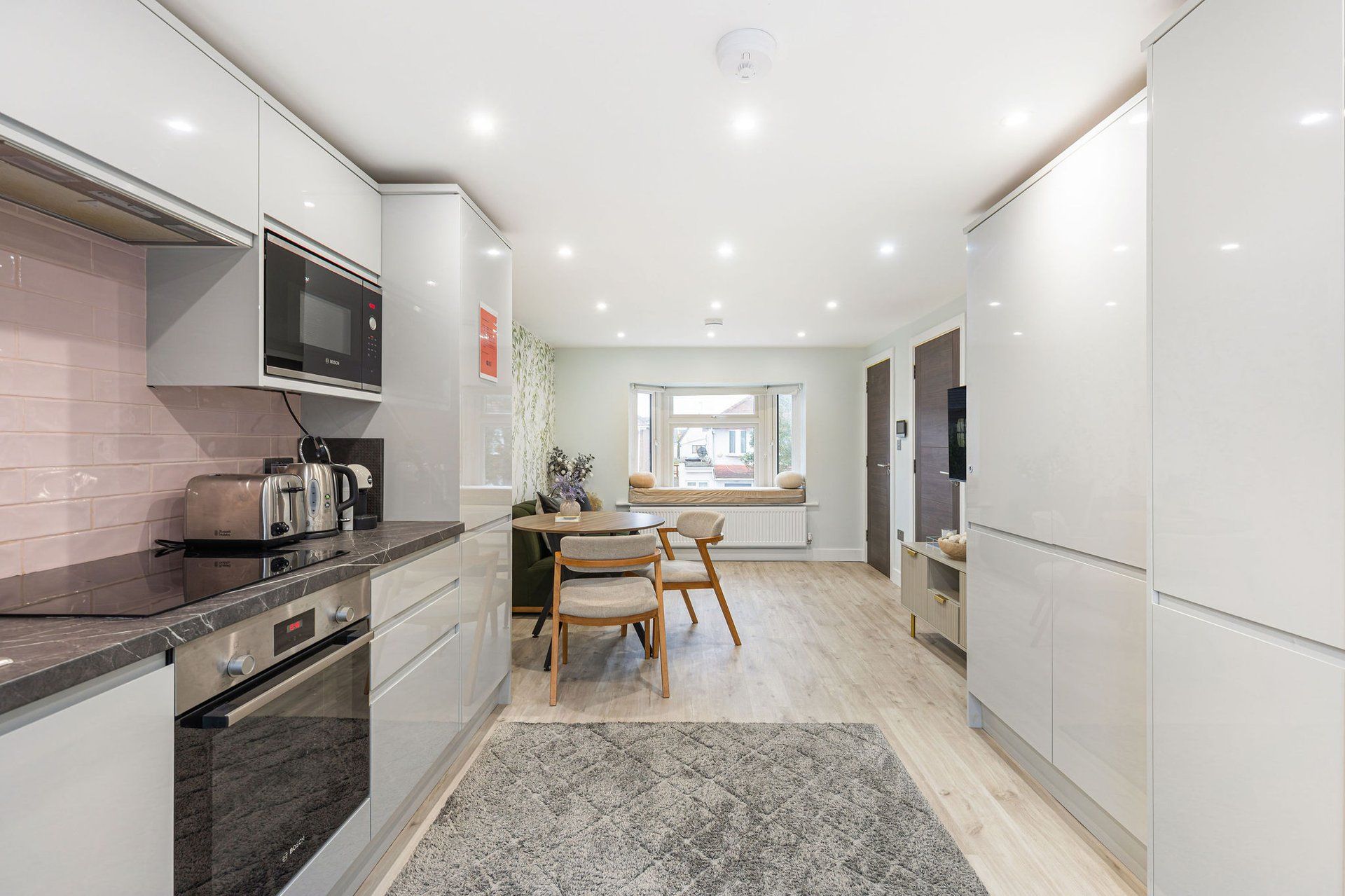 A modern kitchen with a dining area, featuring a built-in oven, microwave, and toaster.