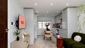 Een moderne woonkamer met een groene bank, een houten salontafel en een televisie aan de muur.