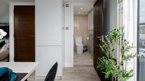 Een moderne keuken met een eethoek, een houten deur en uitzicht op de badkamer.